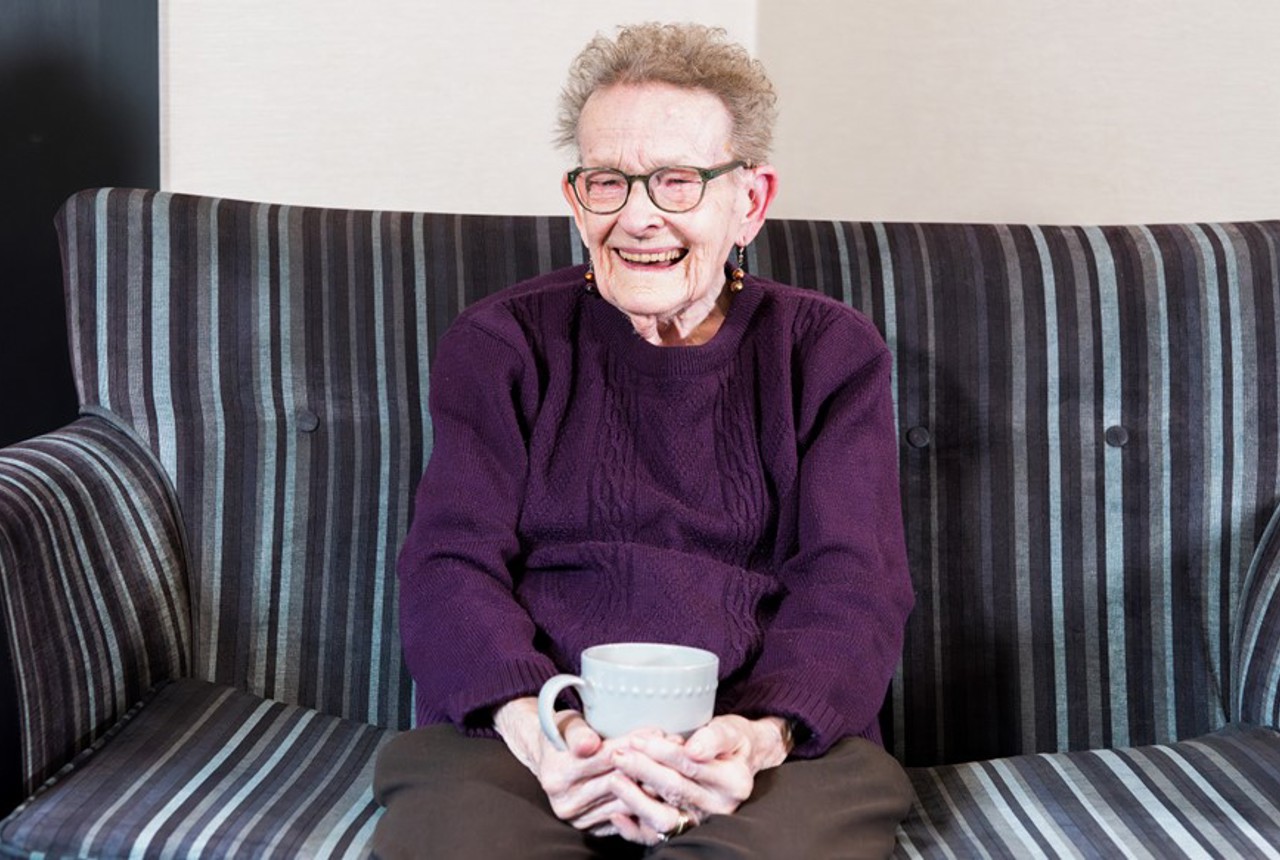 Resident sitting down with a hot drink smiling