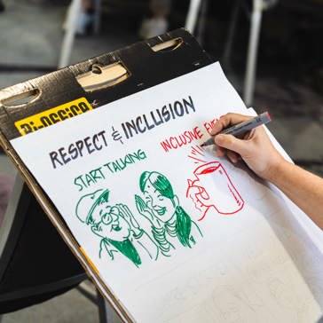 Artist sketching respect and inclusion graphics onto a sketch pad