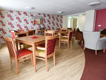 Communal dining area with tables and chairs on a wooden floor