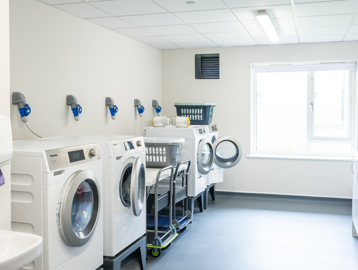 Communal laundry room with large tumble dryers and washing machines