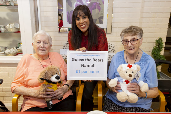 MP Sureena Brackenridge stook between two female residents holding teddy bears, holding a sign saying "Guess the bear's name!"