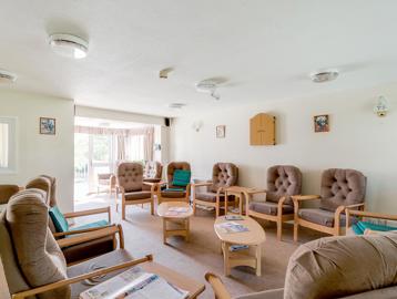 Chairs around the edge of the room in a residents' lounge
