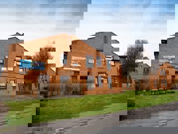 View of the scheme from the roadside with grass verge and trees