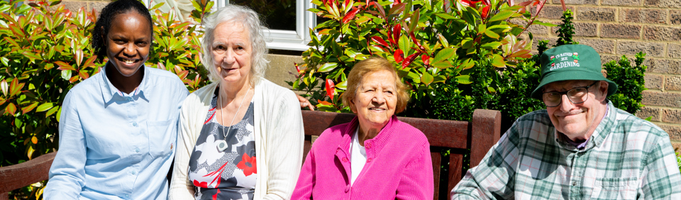 Three residents and a colleague sat on a garden bench on a sunny day
