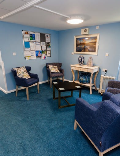 Armchairs in a blue themed room with a coffee table central 