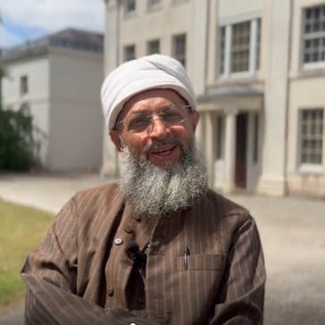 Man with a beard wearing a white headpiece smiling at the camera