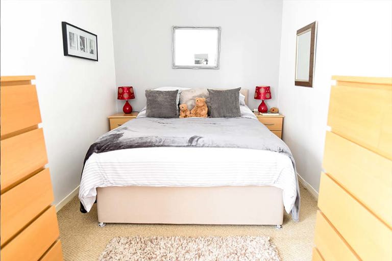 Double bed with two teddy bears on top and side tables either side of the bed