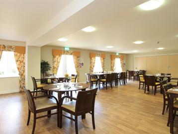 Large communal dining area with wooden flooring and yellow floral curtains
