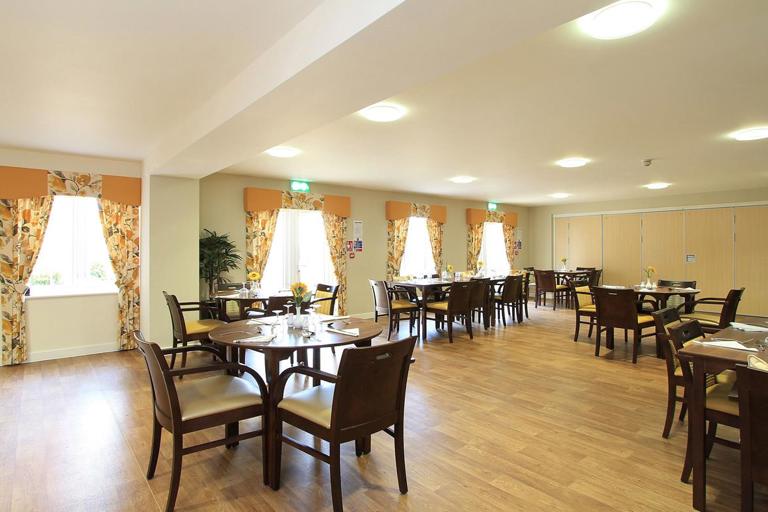 Large communal dining area with wooden flooring and yellow floral curtains