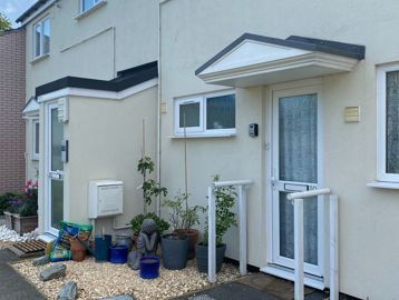 Front doors outside of two resident's properties with small slate areas and plants