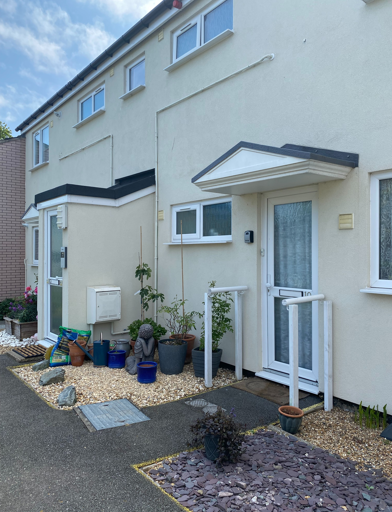 Front doors outside of two resident's properties with small slate areas and plants 