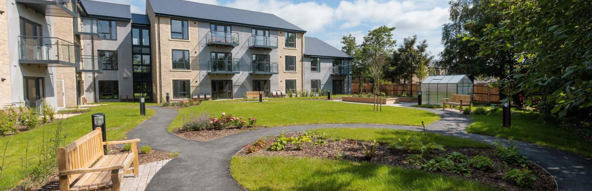 An image showing the outer building of Housing 21's Extra Care scheme, Bowland View surrounded by tree's and grass