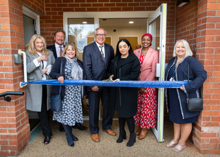 Housing 21 representatives with Councillor Arooj Shah, Leader of Oldham Council, standing outside the new community room door ahead of the ribbon cutting.