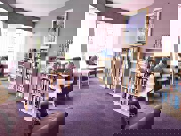 Communal library with soft seating in a purple colour theme