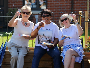 Residents friends smiling outside all holding a glass of prosecco 