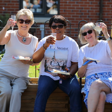 Residents friends smiling outside all holding a glass of prosecco 