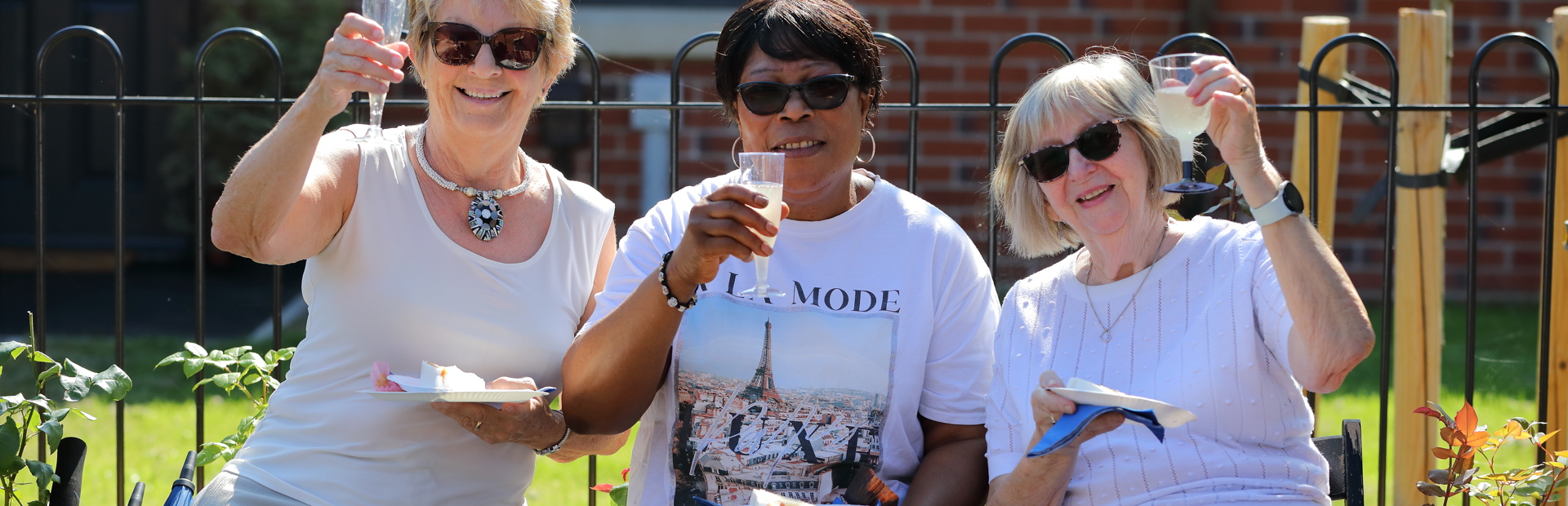 Residents friends smiling outside all holding a glass of prosecco 