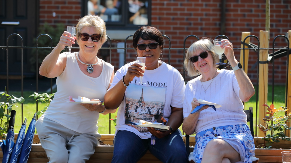 Residents friends smiling outside all holding a glass of prosecco
