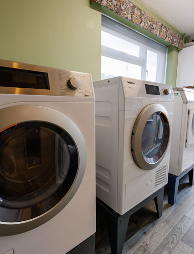 A laundry room containing washing machines and dryers 