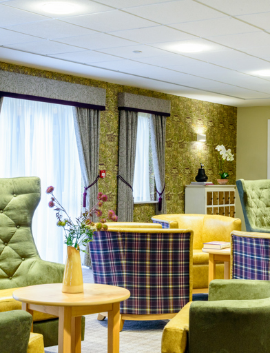 Communal area for residents with high-back soft seating and coffee tables 