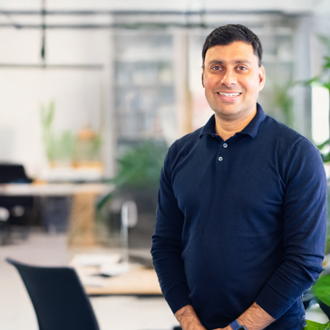 Man in dak blue shirt stood in an office