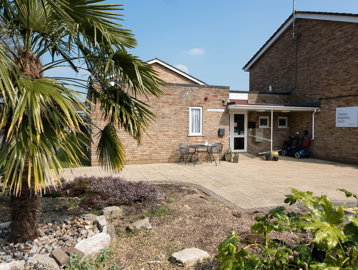 Plants and a large tree set within a rockery area in front of the scheme entrance