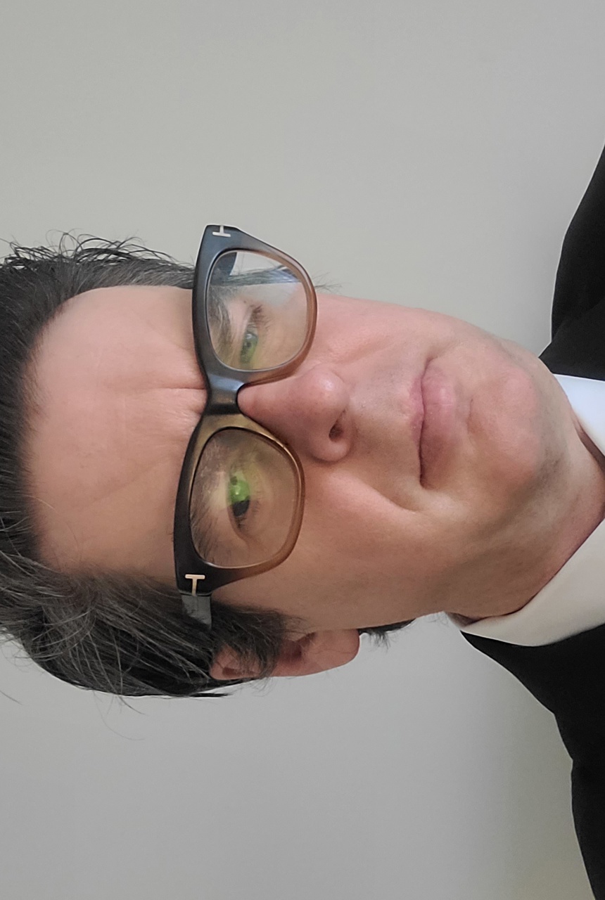 a man with glasses looks at the camera