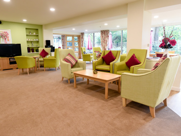 Large communal lounge with a green decor theme and plenty of seats