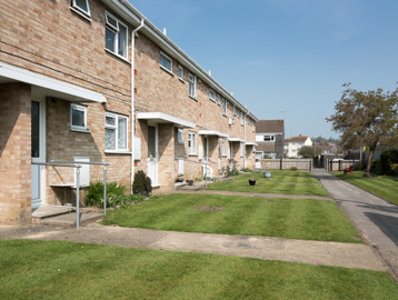Lawns and gardens to the front of resident's homes with pathways leading to the front doors