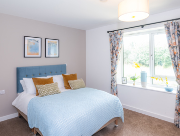 Inside the main bedroom of the show home with double bed and soft furnishings