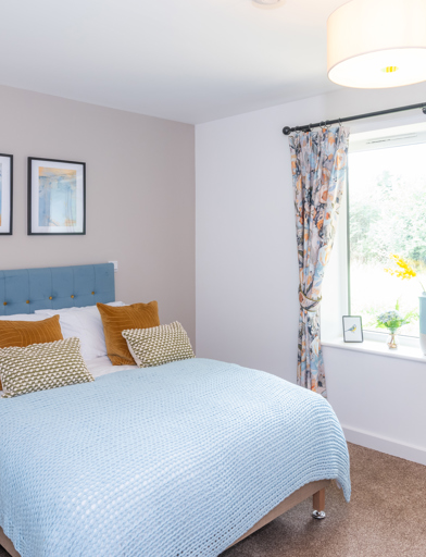 Inside the main bedroom of the show home with double bed and soft furnishings 