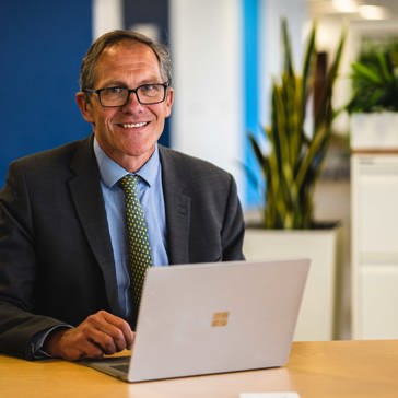 Chief Executive Bruce Moore works from his laptop at a table in the office
