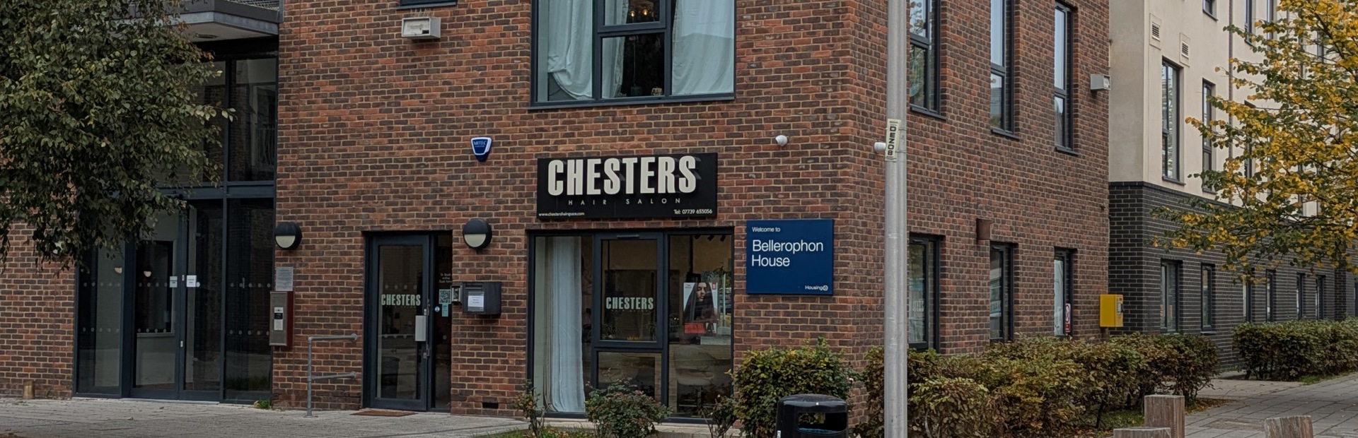 Exterior of Bellerophon House, a tall apartment block with a sign for Chesters Hair Salon on the bottom floor.