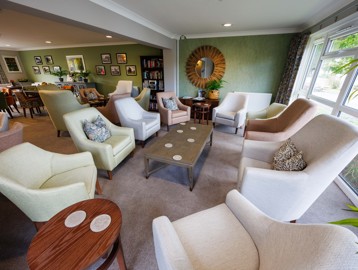 A bright, and vibrant communal lounge area with armchairs around coffee tables