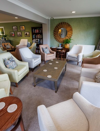 A bright, and vibrant communal lounge area with armchairs around coffee tables 