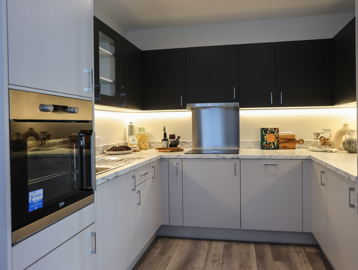 A closer look at the kitchen inside a show apartment at Minterne Apartments with white units and modern lighting
