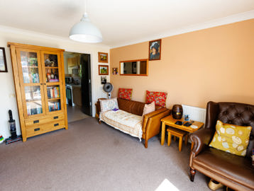 Comfortable living room with a bookshelf and a door that opens into the kitchen area.