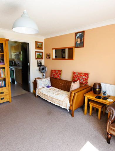 Comfortable living room with a bookshelf and a door that opens into the kitchen area. 