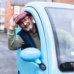 Resident in a car smiling out of the window 