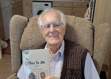 Elderly gentleman in knitted waistcoat, holding up his new poetry book 'this is me'