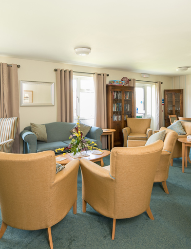 Residents' lounge with soft seating and coffee tables 