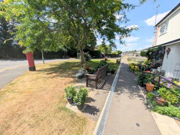 External shot of the gardens including a pathway, bench and trees