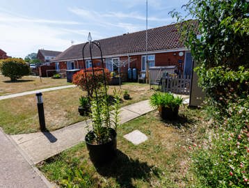 Front of the property with gardens featuring hedges, potted plants and solar-powered lights.