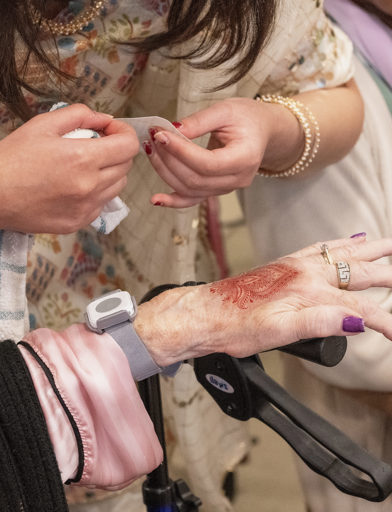 A lady holds her hand out and has a Henna tattoo patterned on the back of her hand 