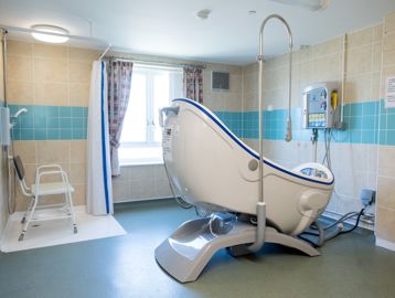 Communal assisted bathroom with bath hoist and walk-in shower