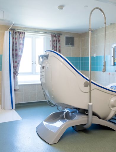 Communal assisted bathroom with bath hoist and walk-in shower 