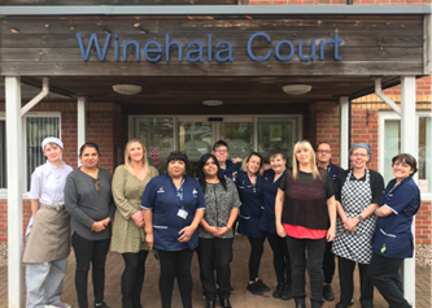 Housing 21 care workers standing outside the front door to Winehala Court.