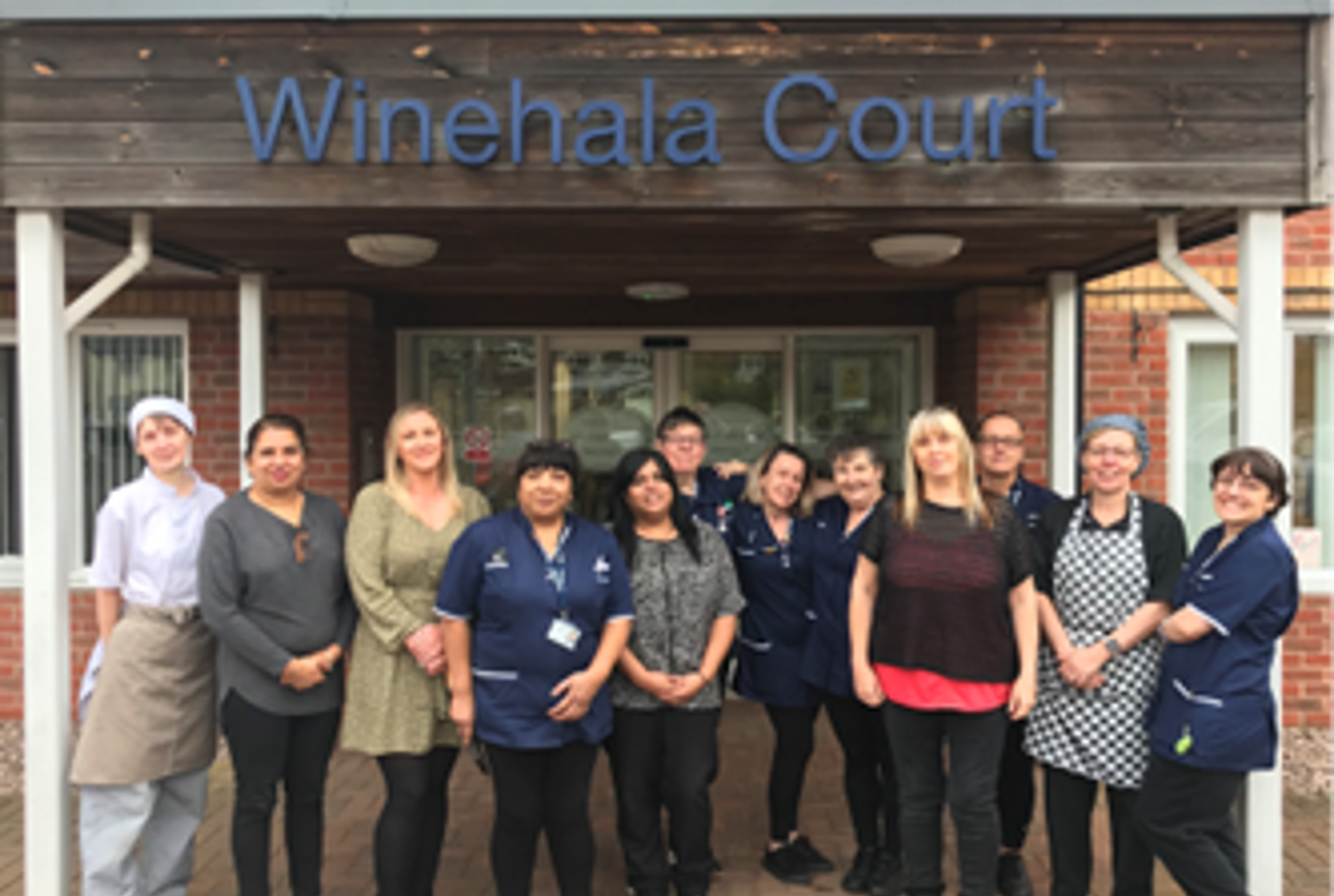 Housing 21 care workers standing outside the front door to Winehala Court.