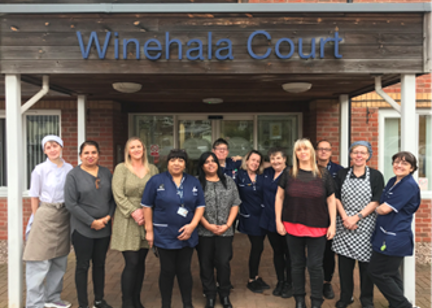 Housing 21 care workers standing outside the front door to Winehala Court.