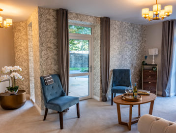 Inside the show home lounge area with chairs, coffee table and bright lighting